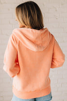 BLONDE WOMAN WEARING A SOLID COLOR ACID WASH FLEECE OVERSIZED 1/4 ZIP KANGAROO POCKET HOODIE.
