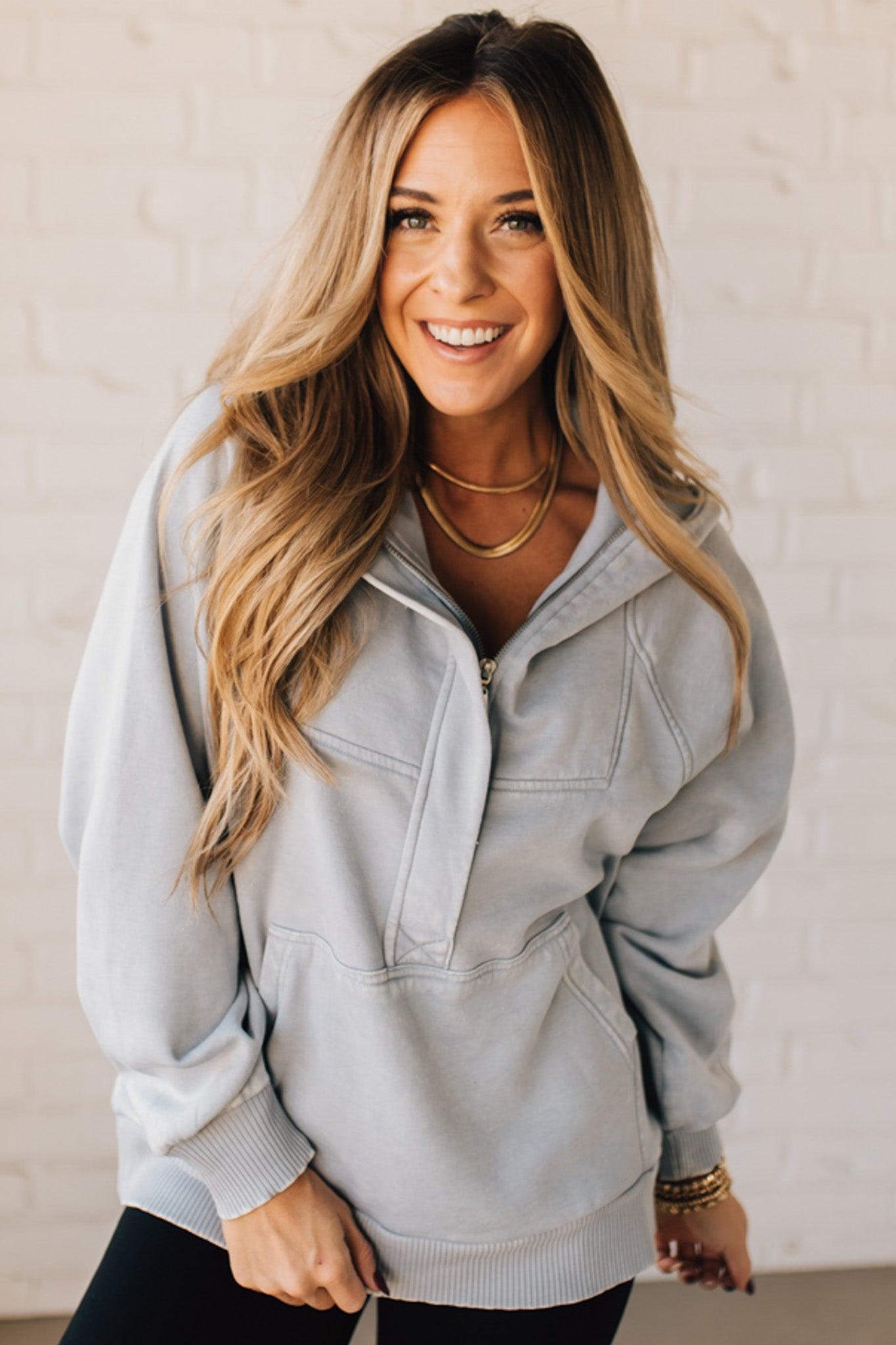 BLONDE WOMAN WEARING A SOLID COLOR ACID WASH FLEECE OVERSIZED 1/4 ZIP KANGAROO POCKET HOODIE.