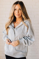 BLONDE WOMAN WEARING A SOLID COLOR ACID WASH FLEECE OVERSIZED 1/4 ZIP KANGAROO POCKET HOODIE.