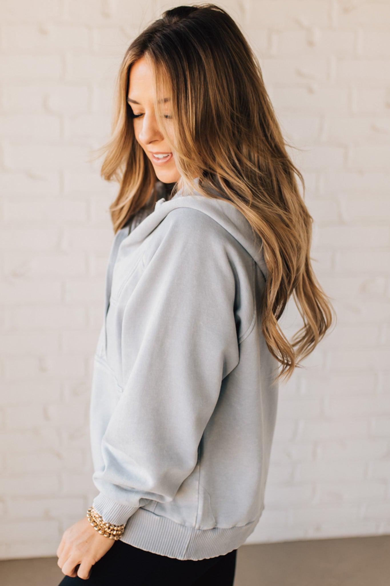 BLONDE WOMAN WEARING A SOLID COLOR ACID WASH FLEECE OVERSIZED 1/4 ZIP KANGAROO POCKET HOODIE.