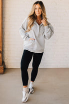 BLONDE WOMAN WEARING A SOLID COLOR ACID WASH FLEECE OVERSIZED 1/4 ZIP KANGAROO POCKET HOODIE.