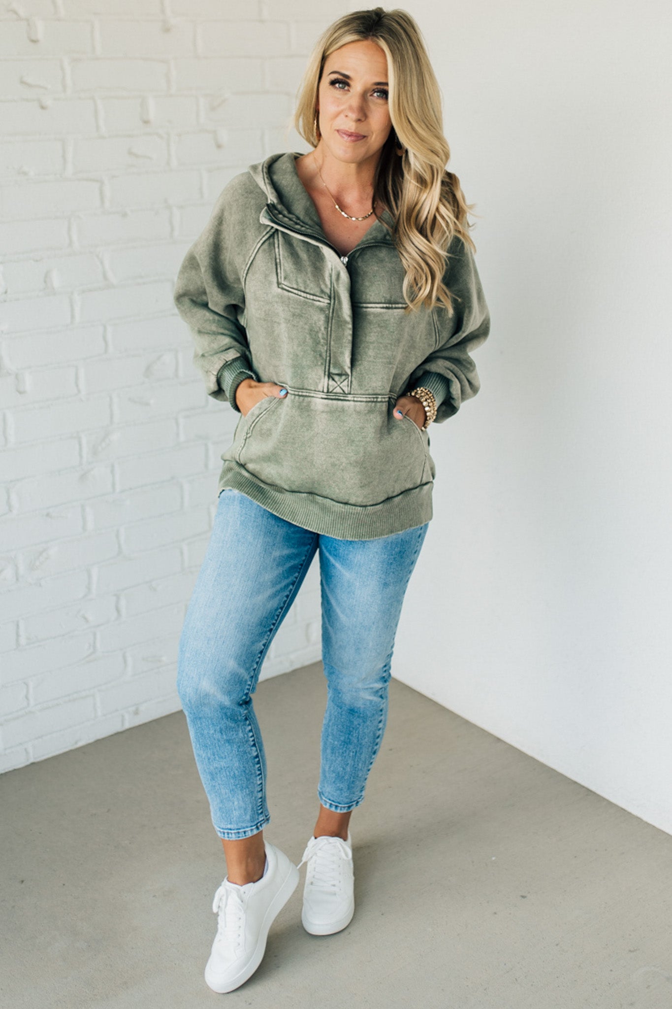 BLONDE WOMAN WEARING A SOLID COLOR ACID WASH FLEECE OVERSIZED 1/4 ZIP KANGAROO POCKET HOODIE.