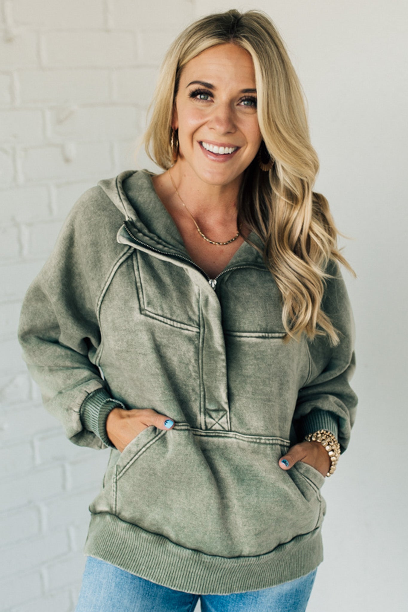 BLONDE WOMAN WEARING A SOLID COLOR ACID WASH FLEECE OVERSIZED 1/4 ZIP KANGAROO POCKET HOODIE.