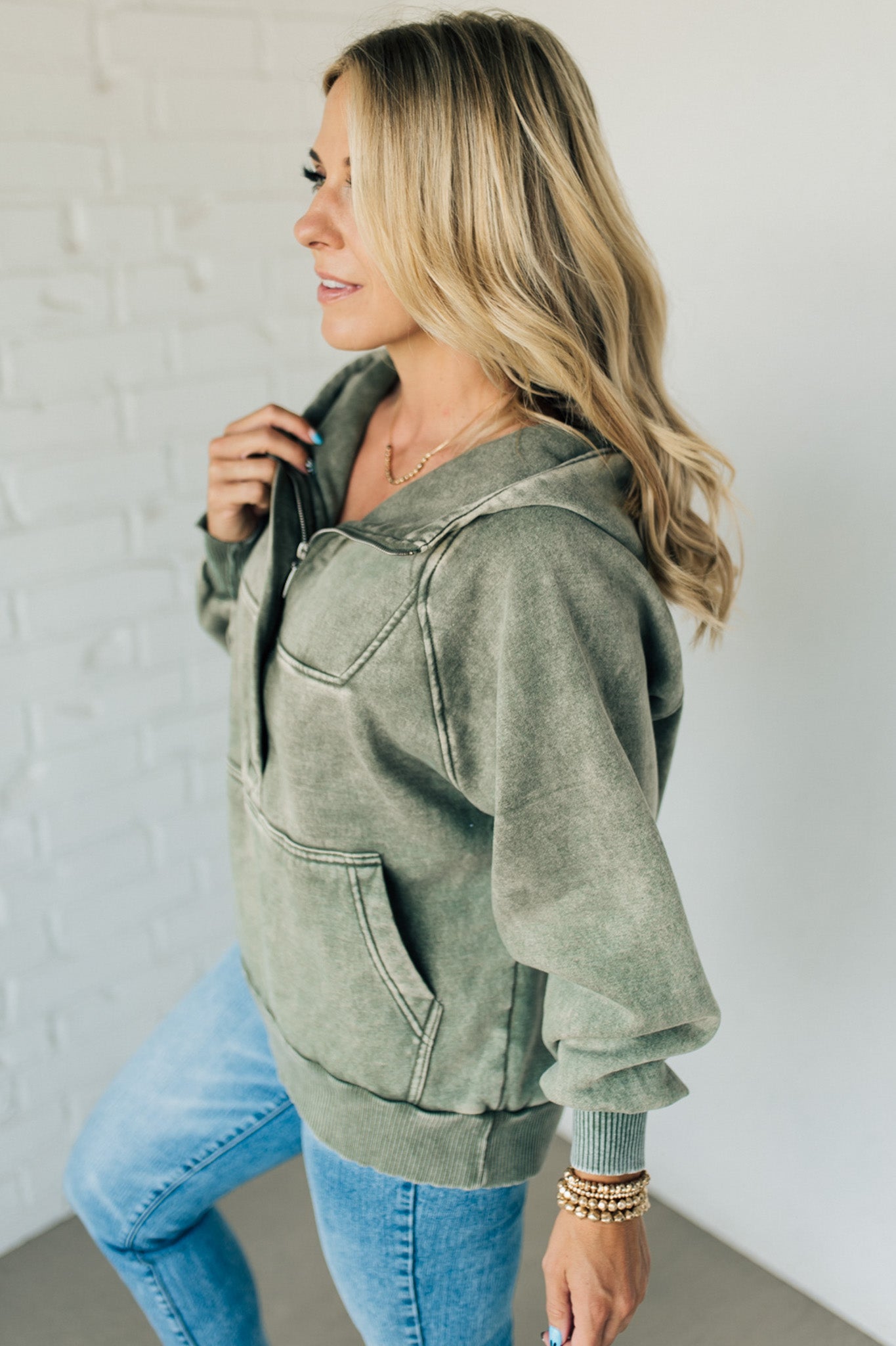 BLONDE WOMAN WEARING A SOLID COLOR ACID WASH FLEECE OVERSIZED 1/4 ZIP KANGAROO POCKET HOODIE.