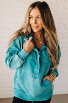 BLONDE WOMAN WEARING A SOLID COLOR ACID WASH FLEECE OVERSIZED 1/4 ZIP KANGAROO POCKET HOODIE.