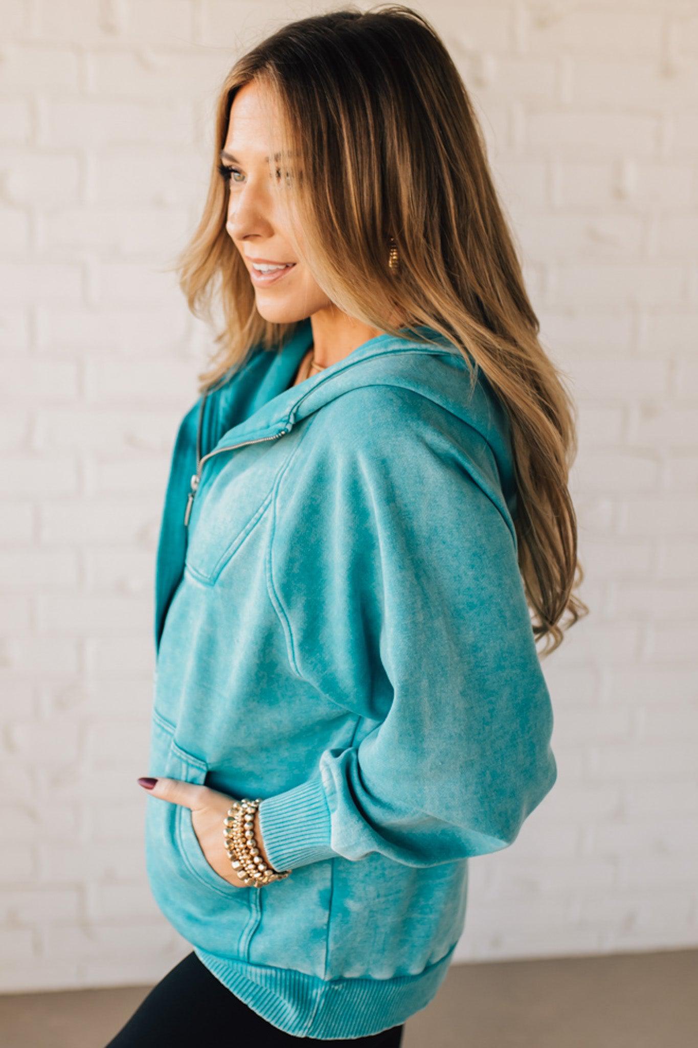 BLONDE WOMAN WEARING A SOLID COLOR ACID WASH FLEECE OVERSIZED 1/4 ZIP KANGAROO POCKET HOODIE.