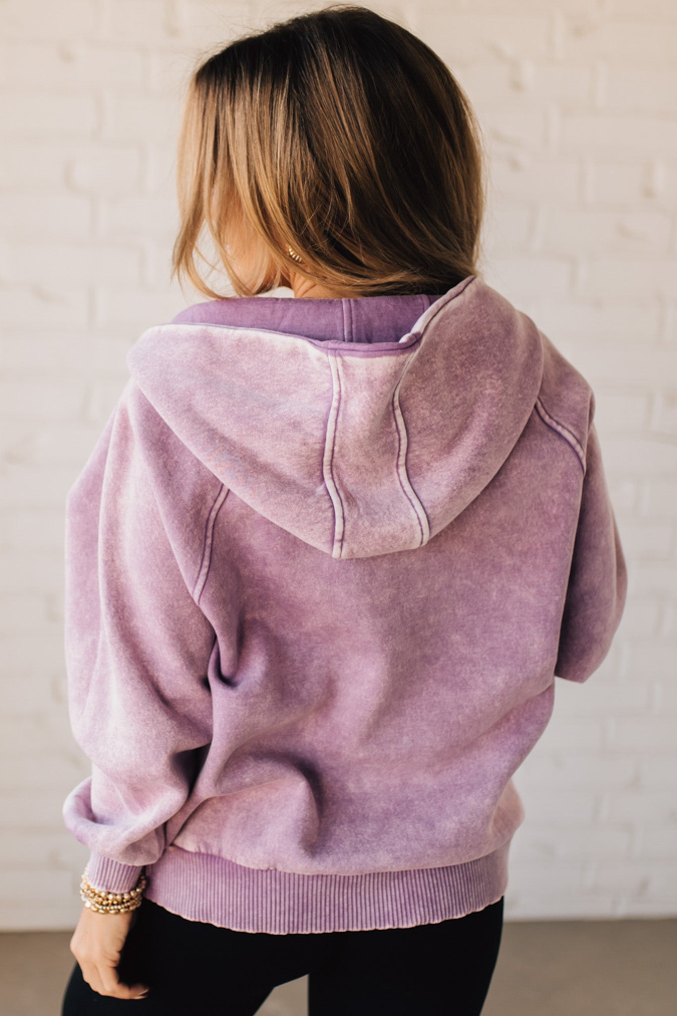 BLONDE WOMAN WEARING A SOLID COLOR ACID WASH FLEECE OVERSIZED 1/4 ZIP KANGAROO POCKET HOODIE.
