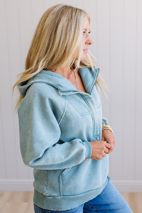 Woman wearing a light blue hoodie and jeans against a plain background