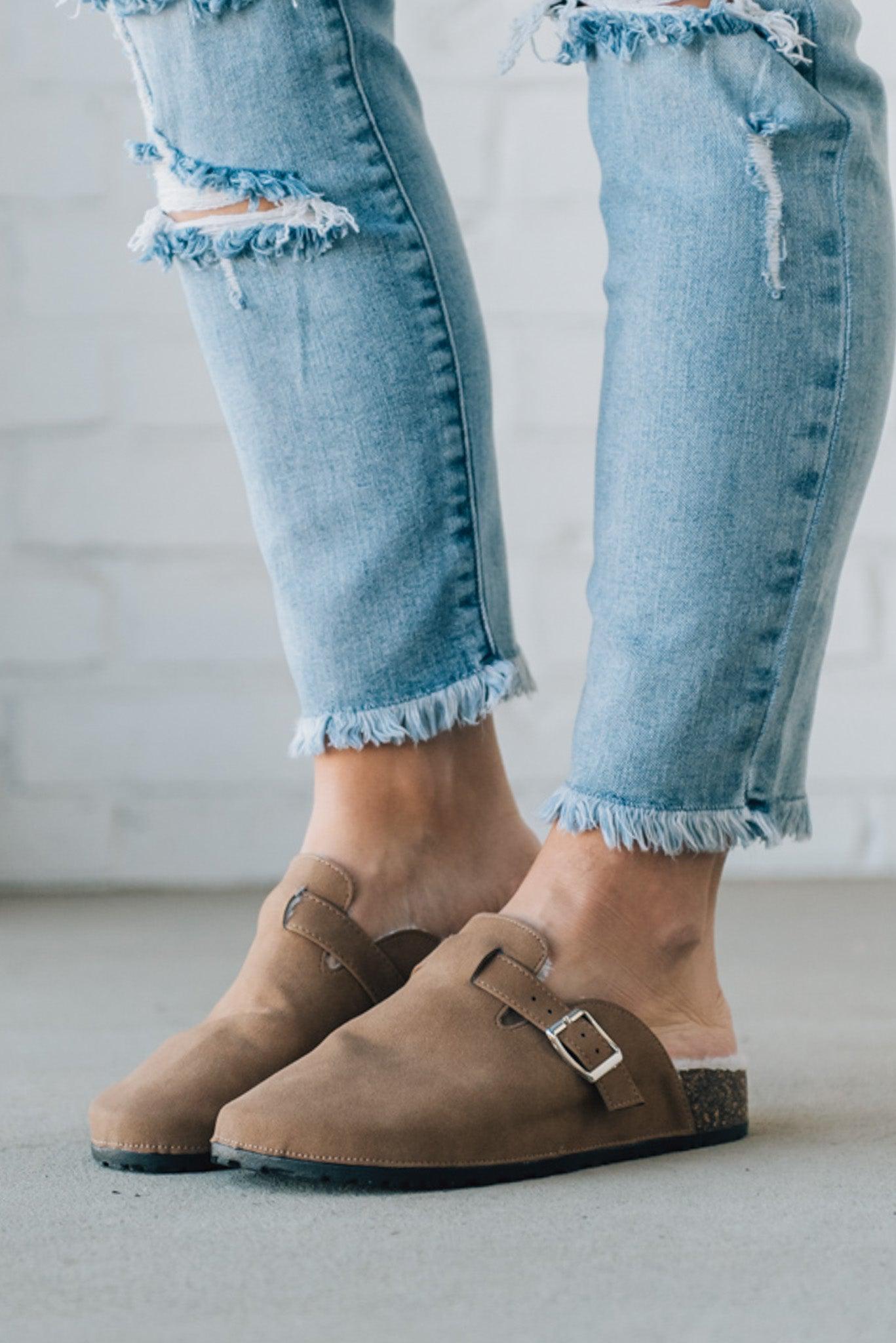 Taupe colored slip on clog with white fur lining and silver buckle