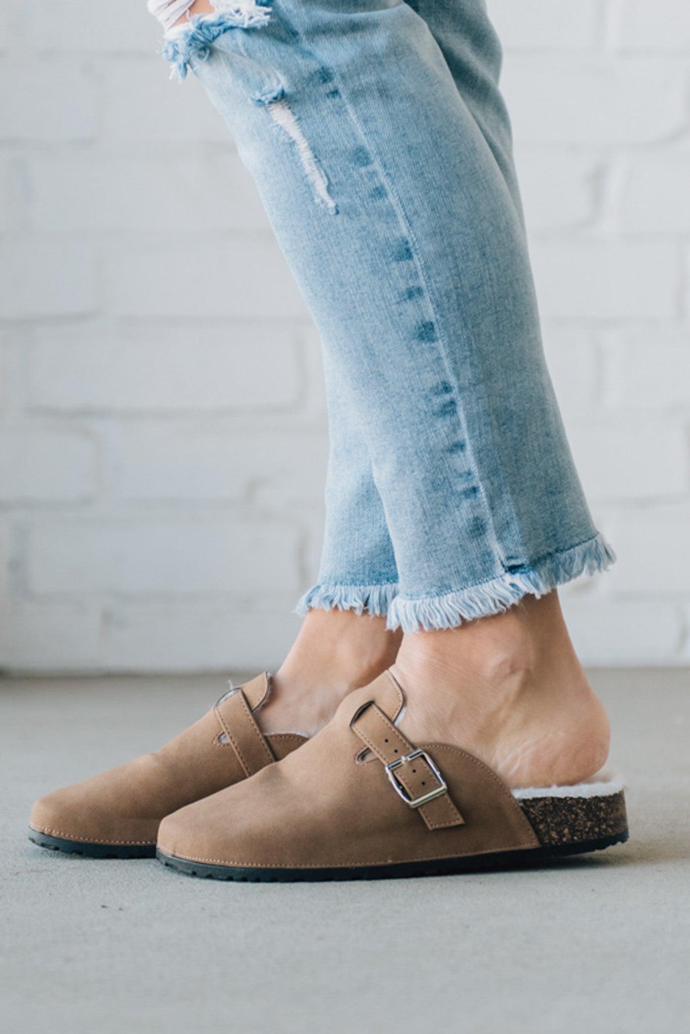 Taupe colored slip on clog with white fur lining and silver buckle
