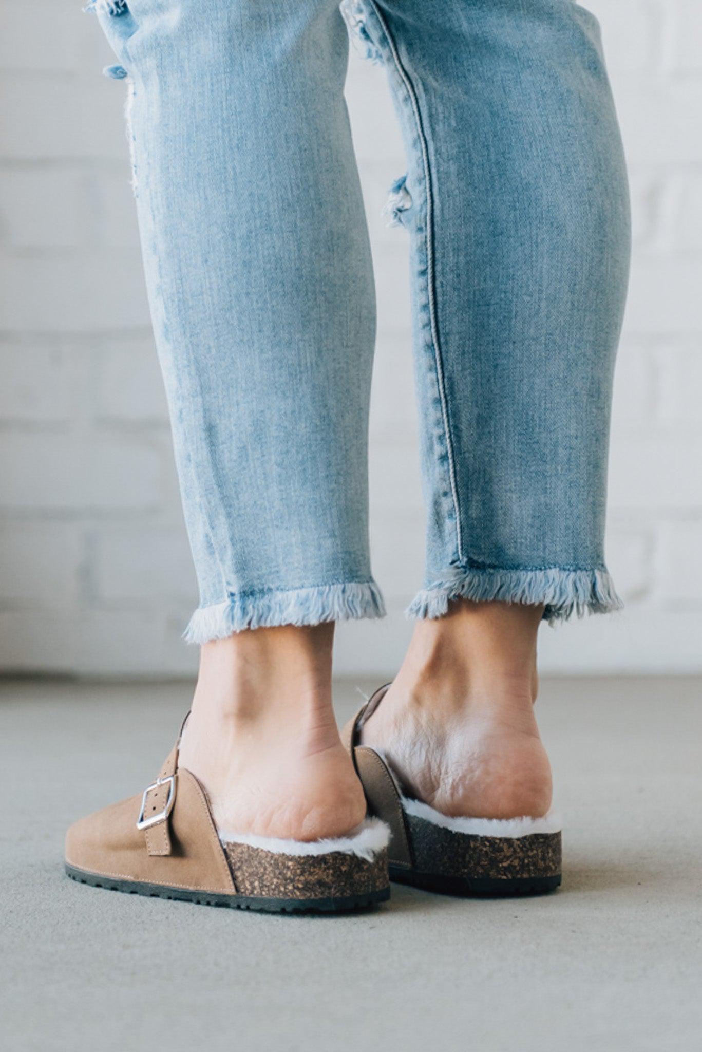 Taupe colored slip on clog with white fur lining and silver buckle