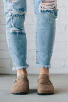 Taupe colored slip on clog with white fur lining and silver buckle