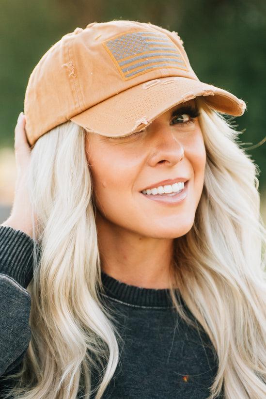 Blonde woman wearing a single color distressed american flag hat.