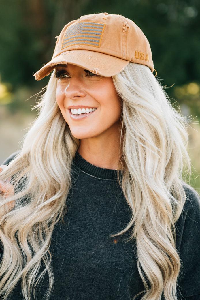 Blonde woman wearing a single color distressed american flag hat.