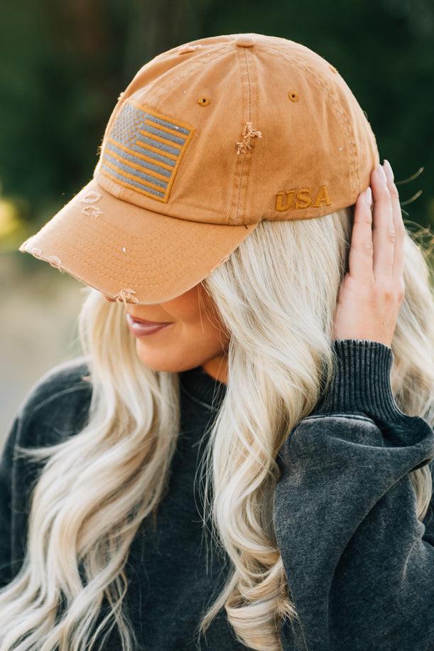 Blonde woman wearing a single color distressed american flag hat.