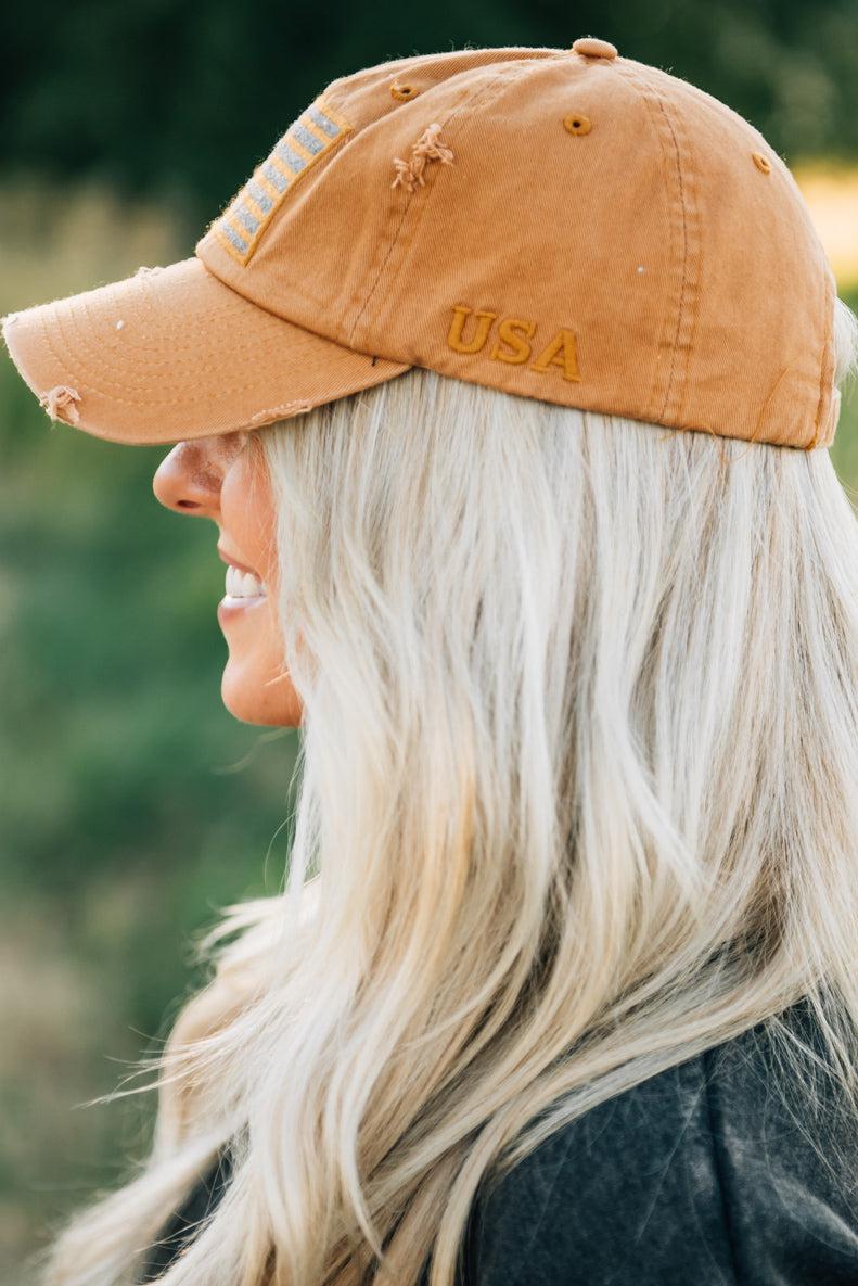 Blonde woman wearing a single color distressed american flag hat.