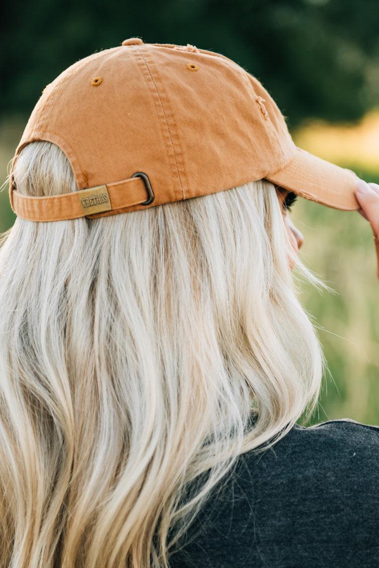 Blonde woman wearing a single color distressed american flag hat.