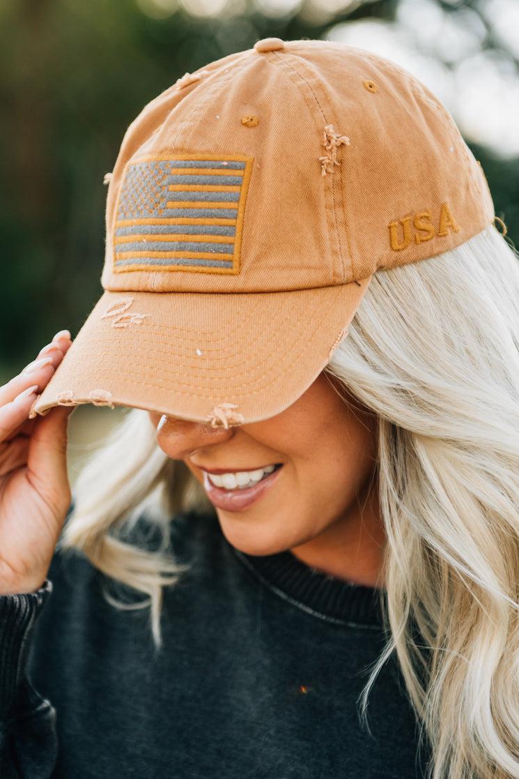 Blonde woman wearing a single color distressed american flag hat.