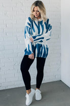 woman wearing an oversized sweater in a trendy ivory and blue graffiti print