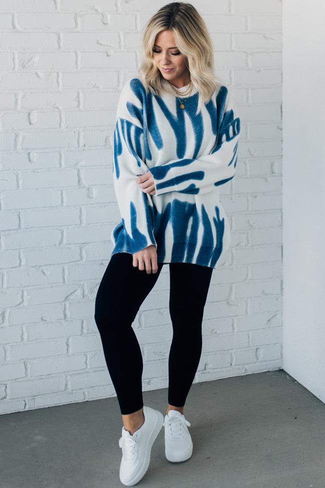 woman wearing an oversized sweater in a trendy ivory and blue graffiti print