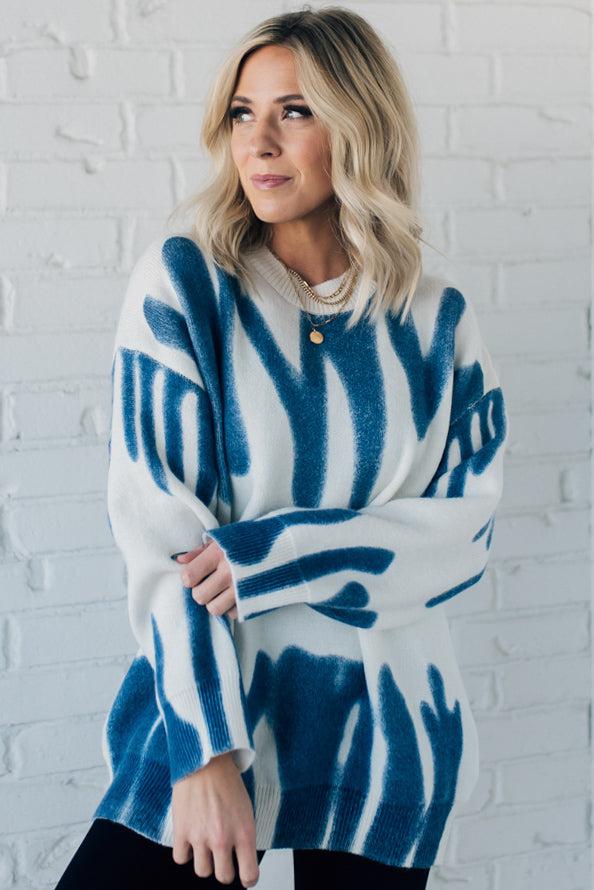 woman wearing an oversized sweater in a trendy ivory and blue graffiti print