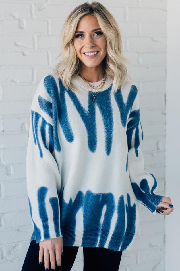 woman wearing an oversized sweater in a trendy ivory and blue graffiti print