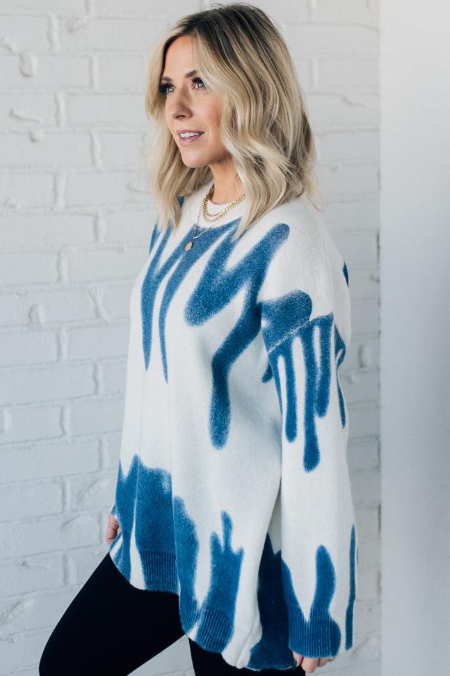 woman wearing an oversized sweater in a trendy ivory and blue graffiti print
