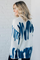 woman wearing an oversized sweater in a trendy ivory and blue graffiti print