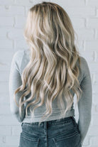 A woman wearing a solid, ribbed, slim fit sweater with a round neck, long sleeves, and tucking it into high-waisted jeans.