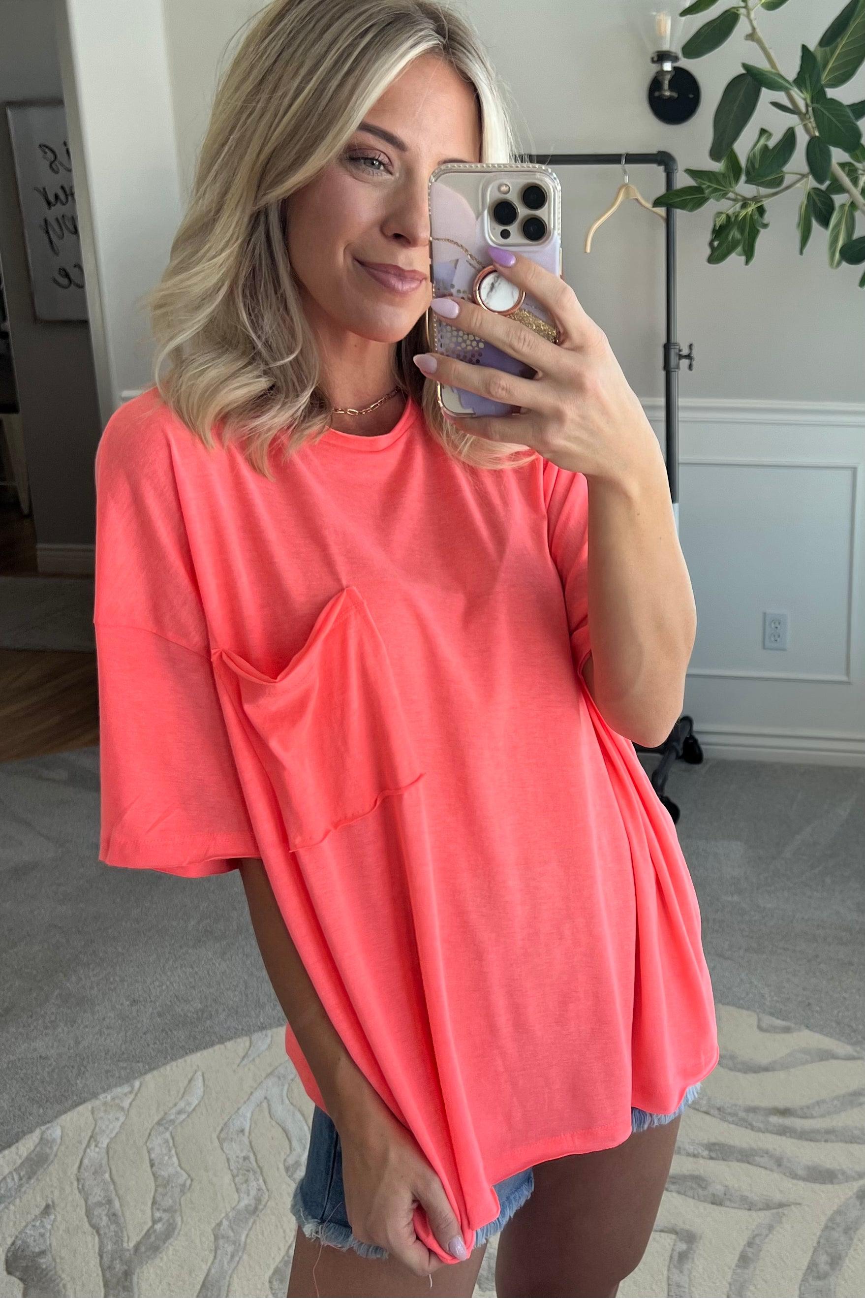 Blonde woman wearing an oversized solid tee with front pocket, and raw scissor cut edges.