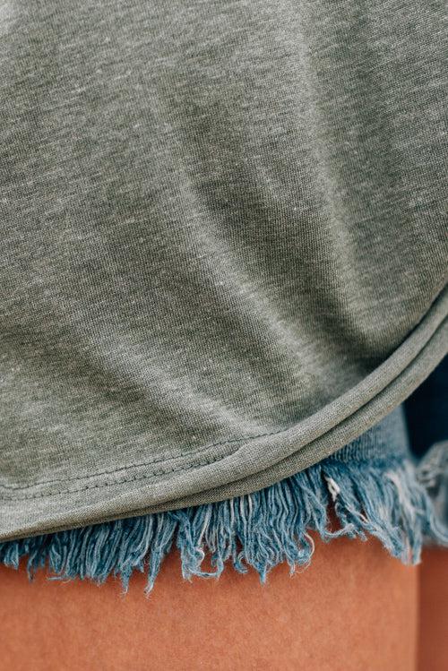 Blonde woman wearing an oversized solid tee with front pocket, and raw scissor cut edges.