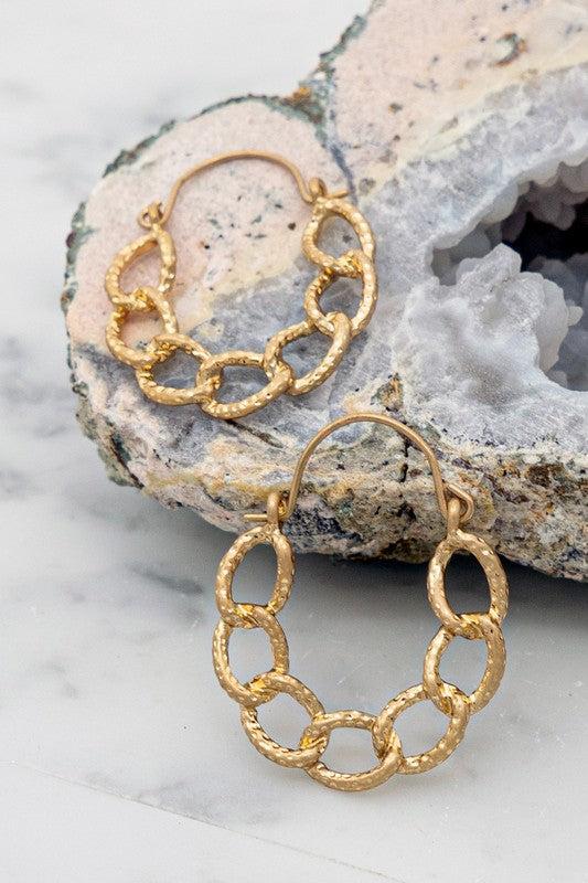 Gold chain earrings on a textured stone surface