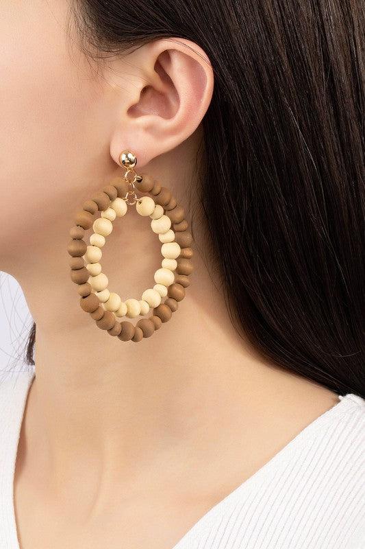 Close-up of a person wearing a pair of beaded hoop earrings.