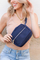 Woman wearing a navy blue waist bag with a neutral background