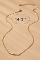 Gold necklace with a bar pendant on a beige background