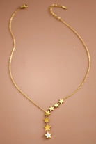 Gold necklace with star-shaped pendants on a brown background