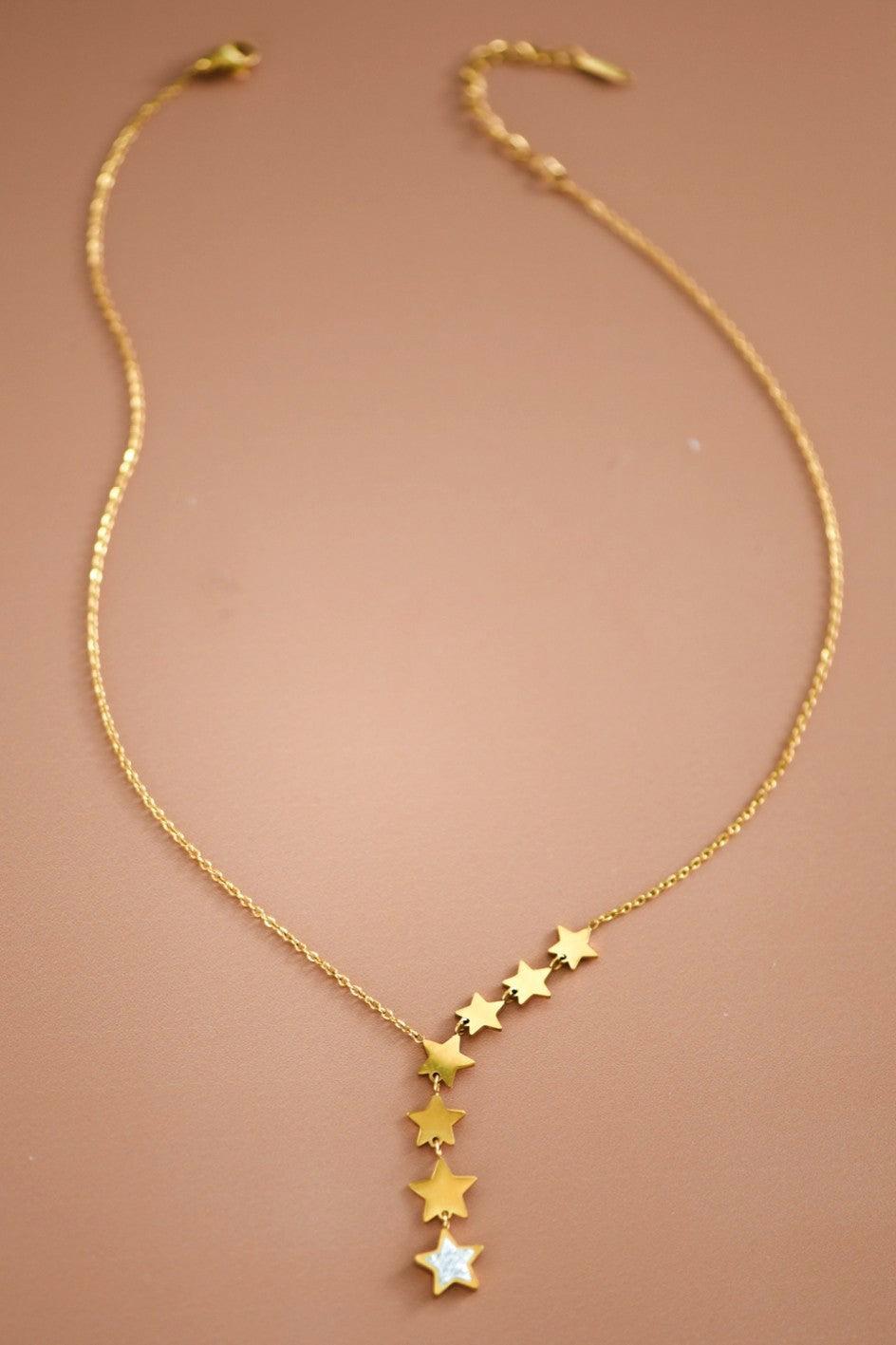 Gold necklace with star-shaped pendants on a brown background