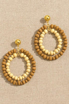 Pair of beaded earrings with gold accents on a beige fabric background