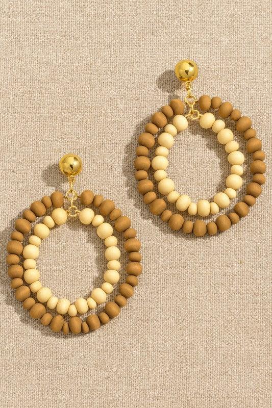 Pair of beaded earrings with gold accents on a beige fabric background