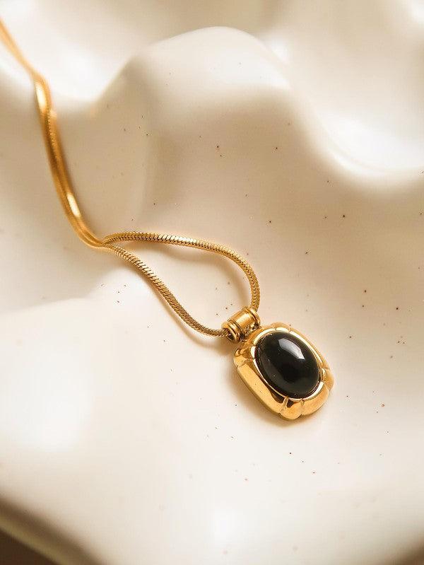 flat lay of black stone necklace with gold trim and gold chain