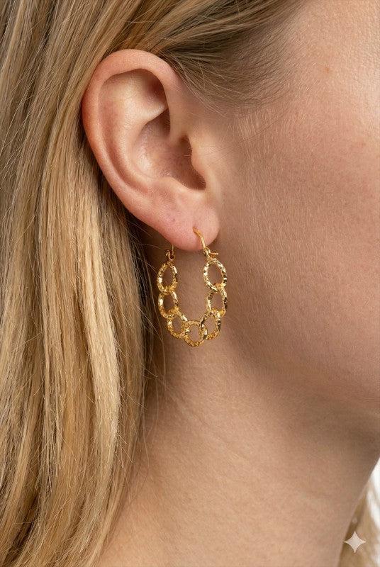 Gold hoop earrings worn by a person with blonde hair.