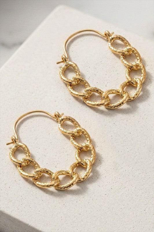 Gold chain hoop earrings on a white surface