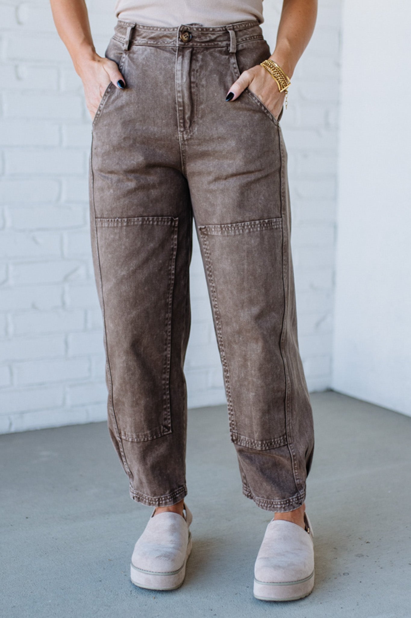 Person wearing brown cargo pants with a white brick wall background