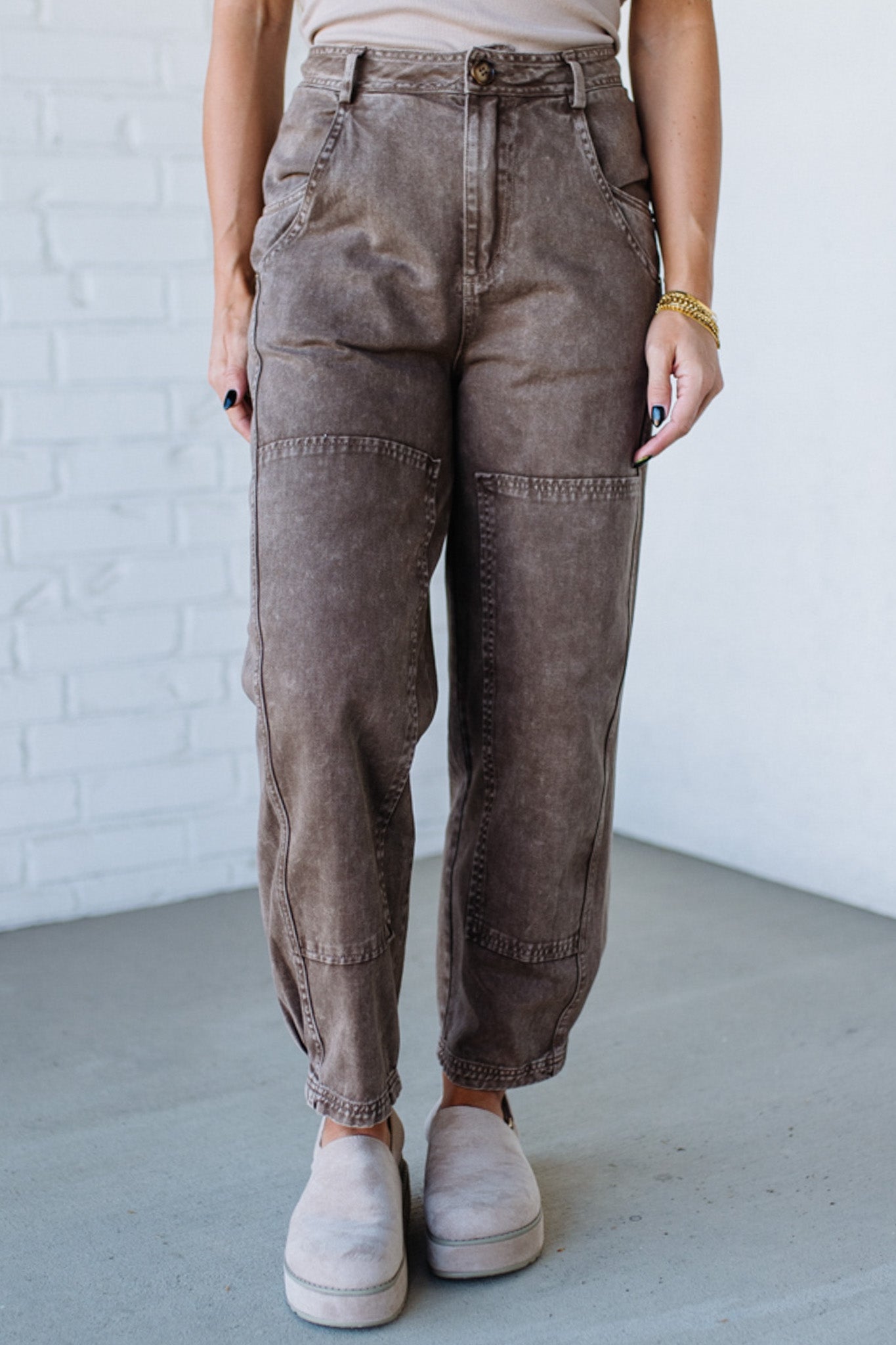 Person wearing brown cargo pants against a white brick wall.
