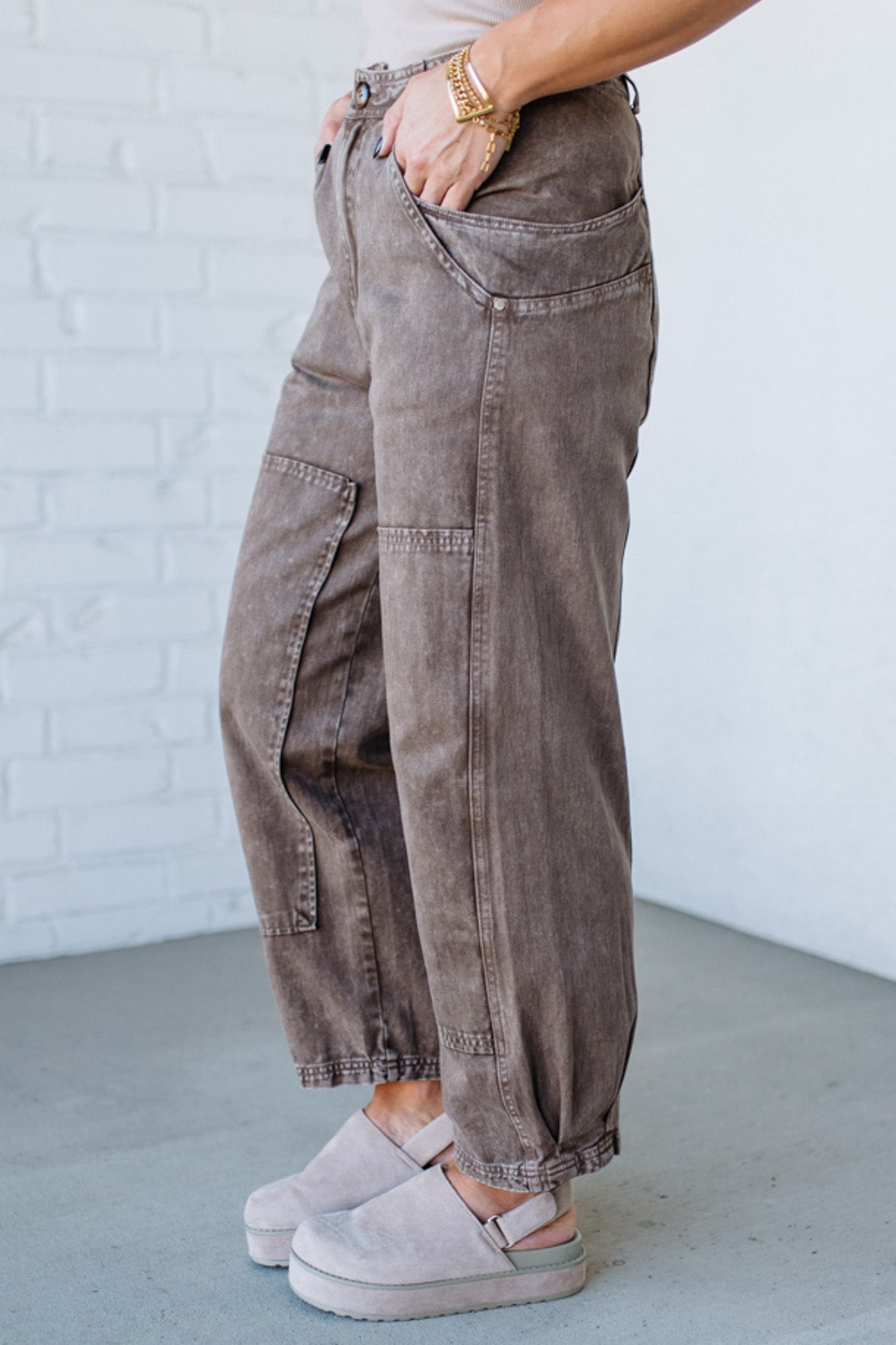 Person wearing brown cargo pants with a white brick wall background