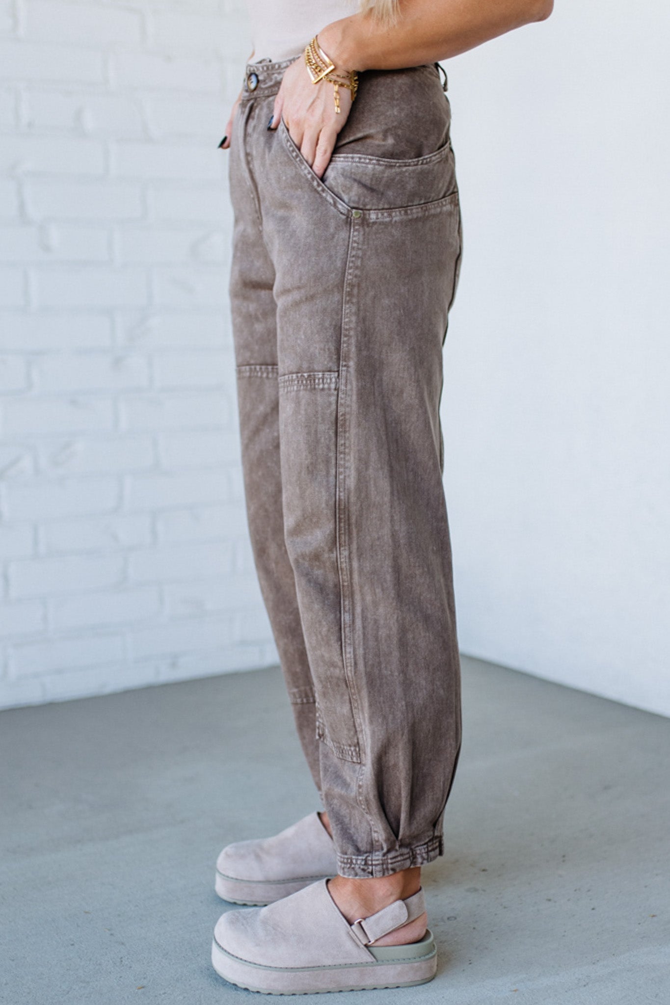 Person wearing brown cargo pants with a white brick wall background