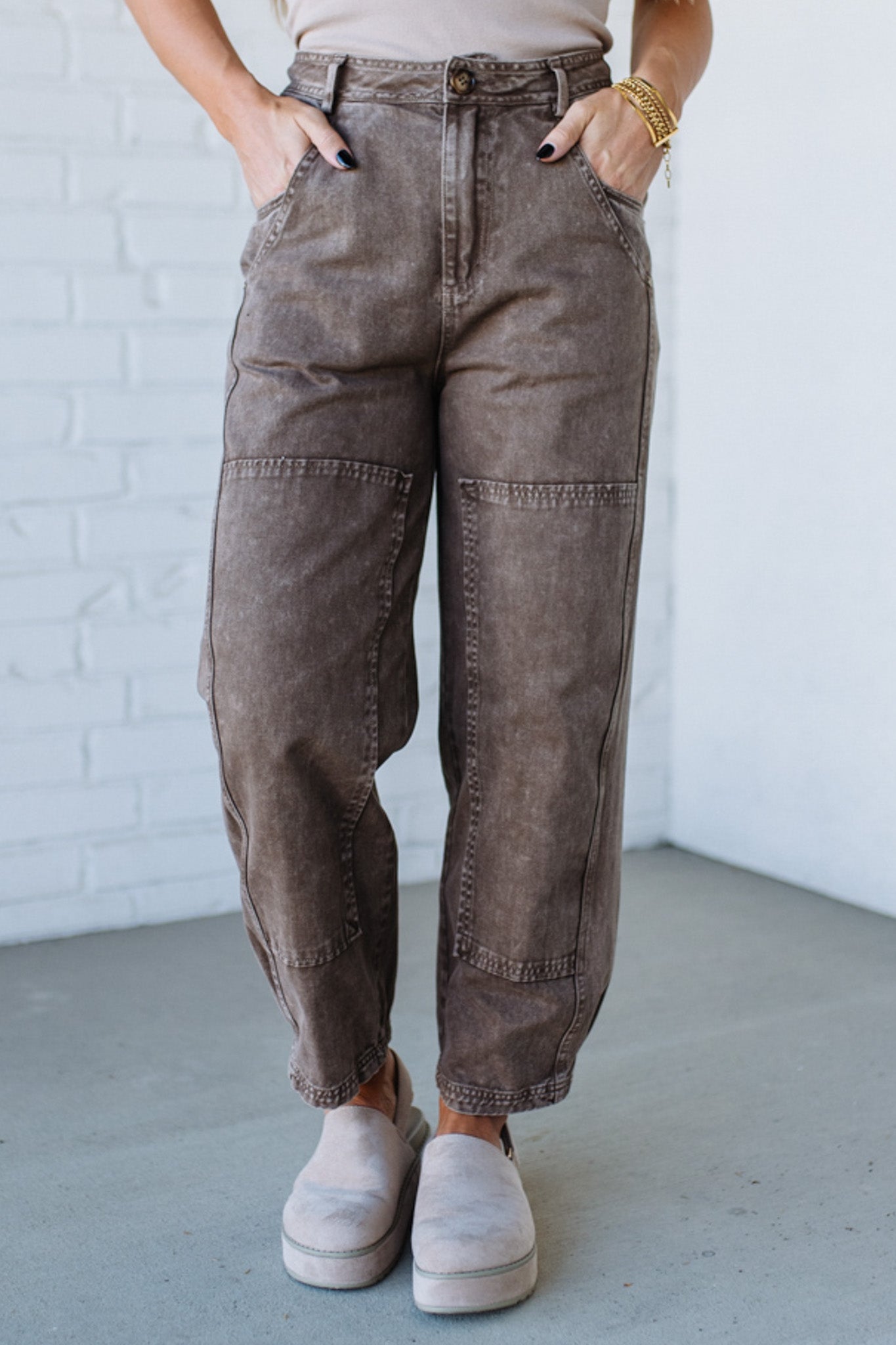 Person wearing brown cargo pants with a white brick wall background