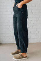 Person wearing dark jeans and brown shoes against a white brick wall.