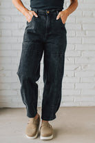 Person wearing black cargo pants with a white brick wall background