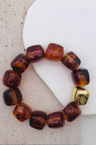 Amber bead bracelet with a gold accent bead shown on a textured surface.